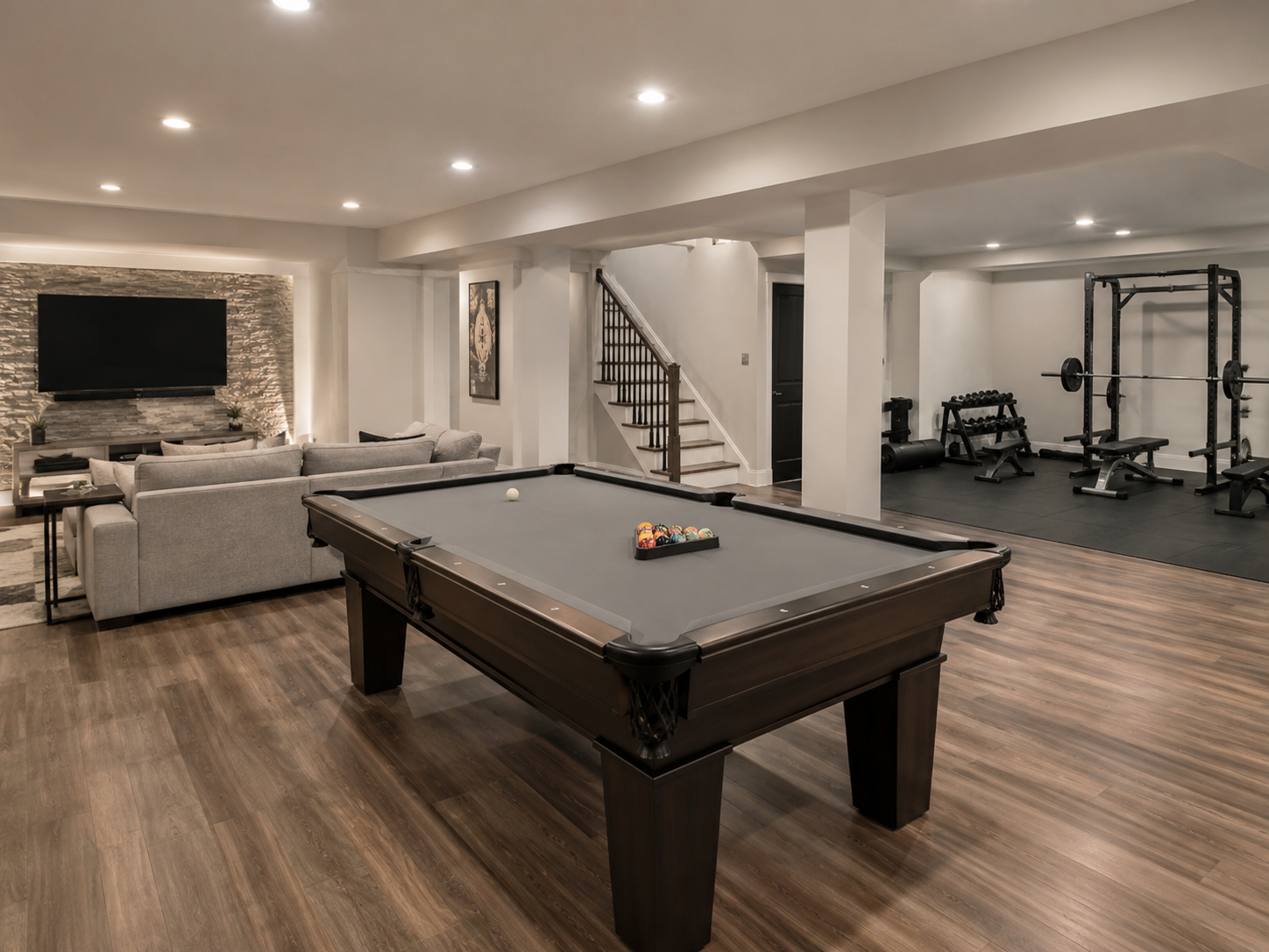 Finished basement recreation room with pool table, home gym, and media wall